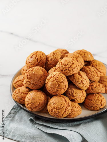 Plate of cookie amaretti on white marble background - traditional Italian Sardinian pastry. Delicious amaretti biscuit cookies made from almond or apricot kernels with copy space