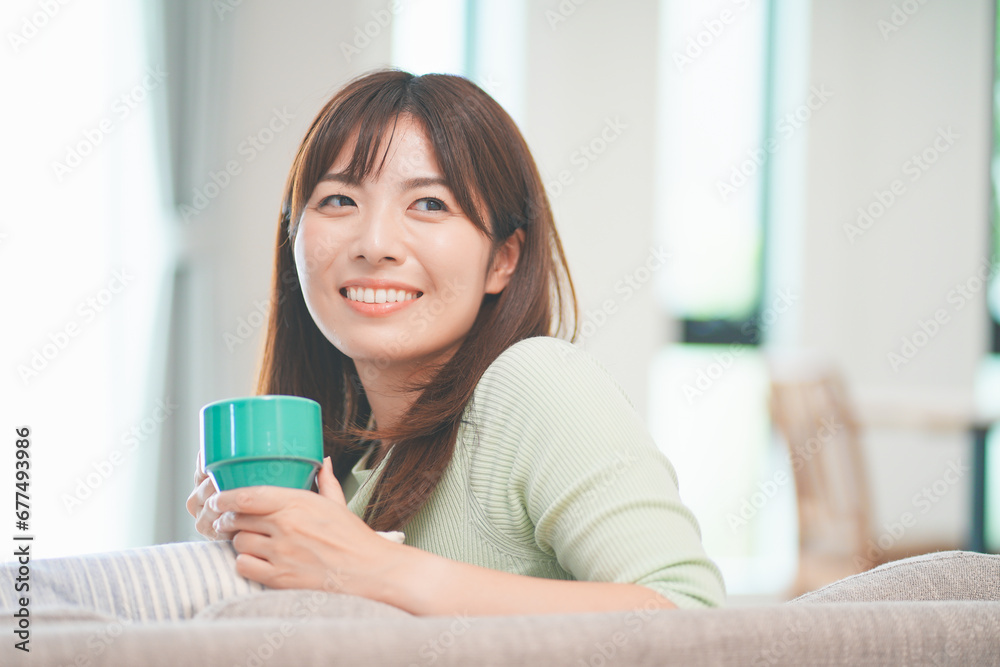 リビングでコーヒーを飲んでリラックスする女性 リビングでコーヒーを飲んでリラックスする女性