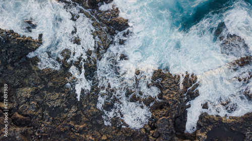 Drone view of Tenerife south coast with Atlantic ocean and strong swell beating against the walls of a rocky cliff  blue rough sea with big waves with foam crashing against the rocks