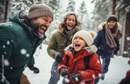 Kids and parents laughing during snowball fight in the forest. Happy family during a winter walk in the park.
