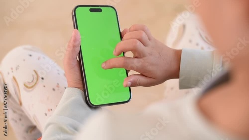 Children’s hands hold phone with green screen. Kid hold phone by two hands. close up green screen. 