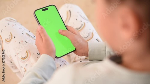 Children’s hands hold phone with green screen. Kid hold phone by two hands. close up green screen. 