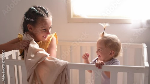 Two small girls stands in baby crib. Children fun and play. Good joyful mood. Happy childhood