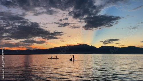 Slow Motion Sunset Serenity. Paddleboarding on Phayao Lake in Thailand. People Silhouetted Against the Gorgeous Evening Sky.