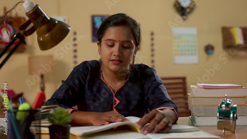 Indian teenager dedicated girl preparing for government or public examination by reading at home - concept of concentration, education and aspirant.