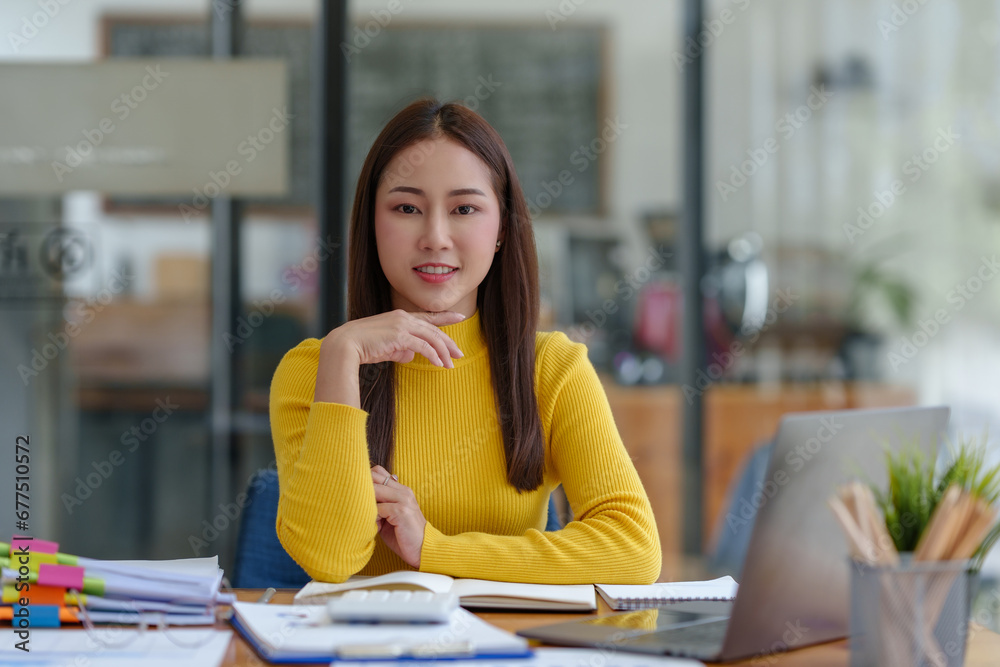 Happy young Asian woman smiling while working with laptop in office. Happy young Asian woman smiling while working with laptop in office.