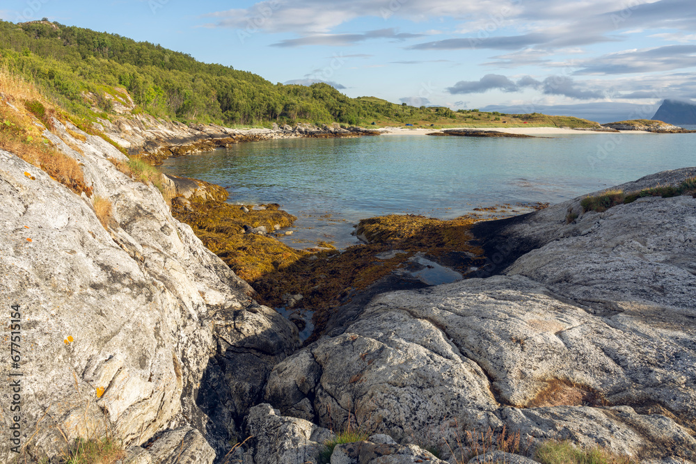 A serene summer morning by the turquise sea and rocky shore in Sommarøya island, in the Tromsø Municipality in Troms og Finnmark county, Norway.