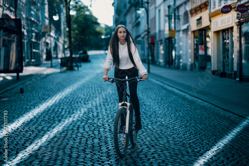 A young woman smiles while cycling in the city. © luchschenF