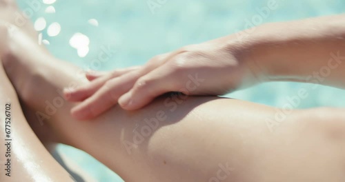 Female hand spray sunscreen cream massage legs pool vacation close up