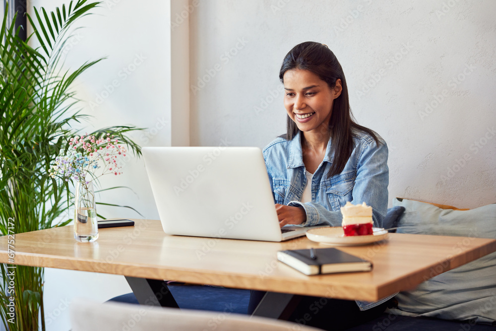 Smiling woman sitting in a cafe using laptop Smiling woman sitting in a cafe using laptop