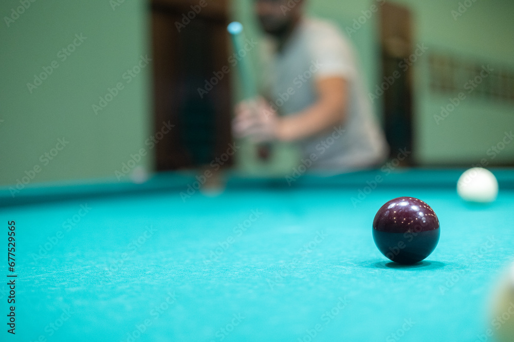 A man plays billiards effectively and hits the ball with a cue. A
