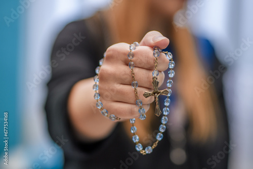 Różaniec - symbol wiary chrześcijańskiej owinięty wokół ręki młodej kobiety photo