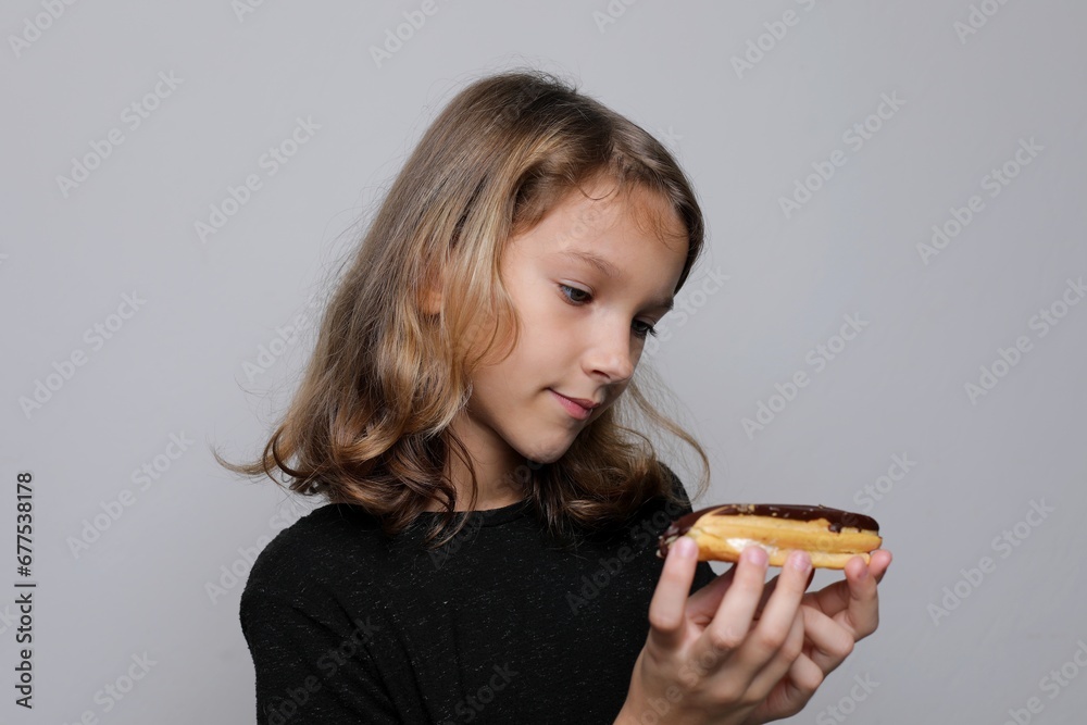 A junior schoolgirl girl holds a plate of dessert and doubts, looking sad A junior schoolgirl girl holds a plate of dessert and doubts, looking sad