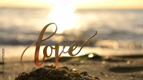 Black outlines of word Love at dawn and sunset on the background of sea waves on seashore. Stick contours in shape word Love in sand of setting and rising sun. Concept Love infatuation Valentine's Day
