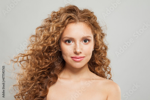 Redhead female model with curly long brown hairstyle on white background. Woman with wavy hair