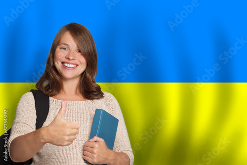 Beautiful young woman student against Ukrainian flag background. Travel, education and learn language in Ukraine concept photo