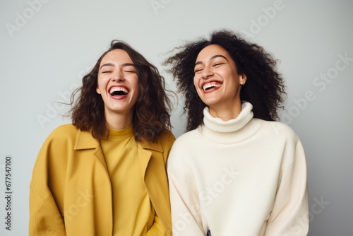 Two interracial best friends laughing and having a good time together in a studio. Portrait of lovely young women, beautiful, diversity, smiling isolated on pastel background. photo