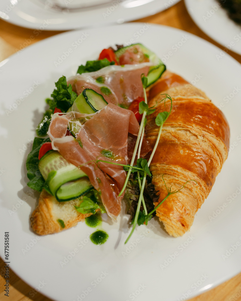 croissant sandwich with cherry tomatoes jamon and cucumber