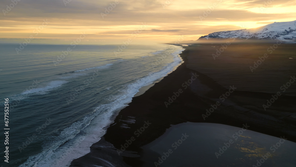 Atlanic coastline black sand beach with waves crashing on icelandic shore, beautiful natural landscape in iceland. Drone shot of majestic scenic route and nordic scenery. Slow motion.
