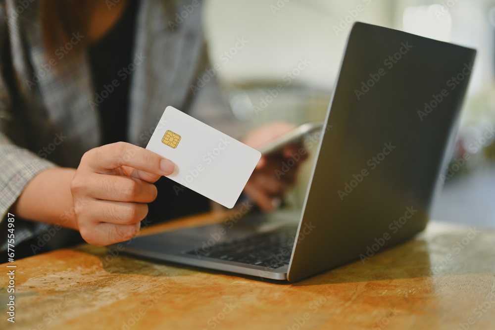 Young woman holding credit card using laptop doing online banking transaction or shopping in online store Young woman holding credit card using laptop doing online banking transaction or shopping in online store