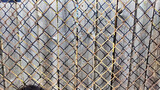 Chain link iron net with stack of wooden planks behind. Abstract background with metal mesh and wooden boards. Pattern, space for text, copy space