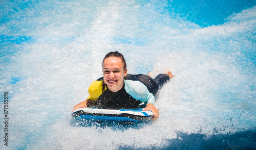 Beautiful young woman surfing on a wave simulator at a water amusement park photo