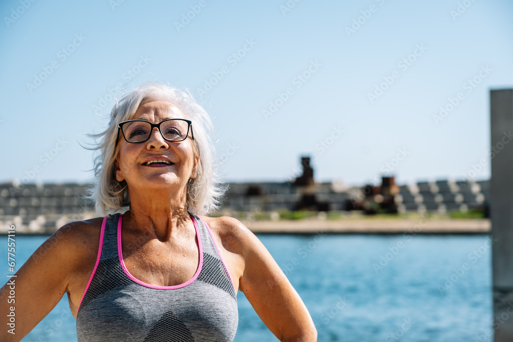 Old sportive woman inhaling air next to a lake Old sportive woman inhaling air next to a lake