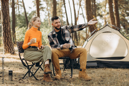 Couple drinking tea by their tent in forest