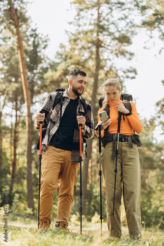 Couple hiking with bags and walking sticks in forest © Petro