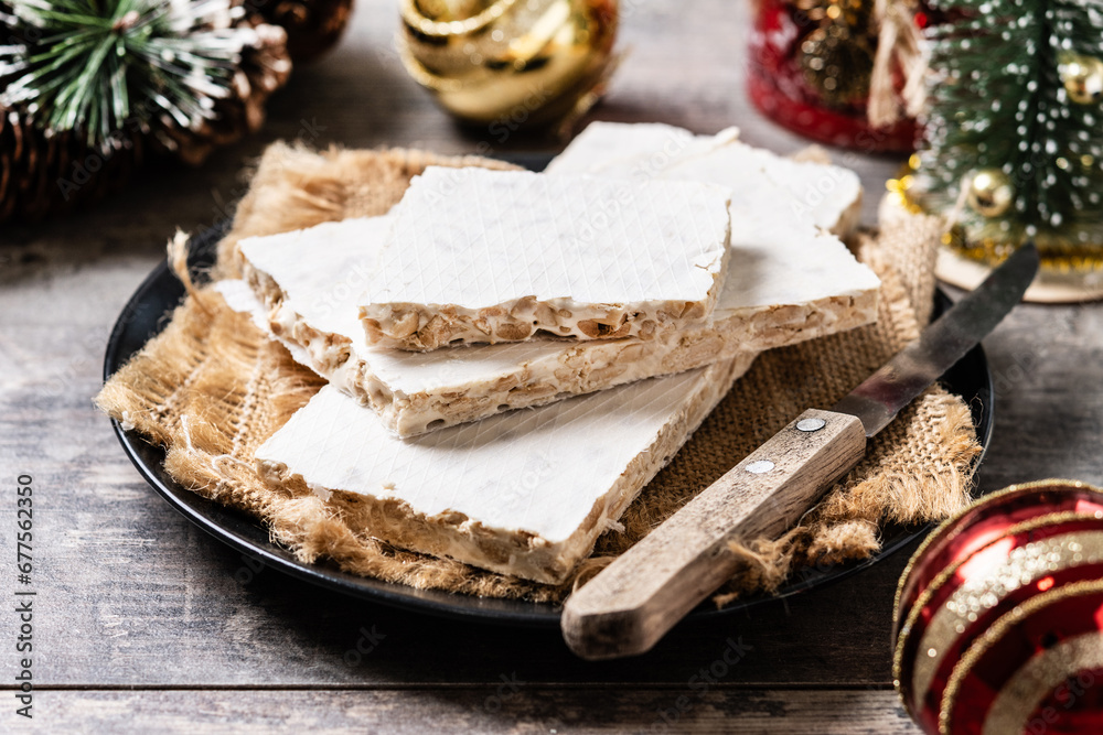 Traditional Christmas sweet, pieces of delicious almond nougat on wooden table Traditional Christmas sweet, pieces of delicious almond nougat on wooden table