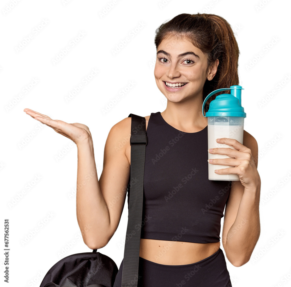 Athletic Caucasian woman holding protein shake showing a copy space on a palm and holding another hand on waist.