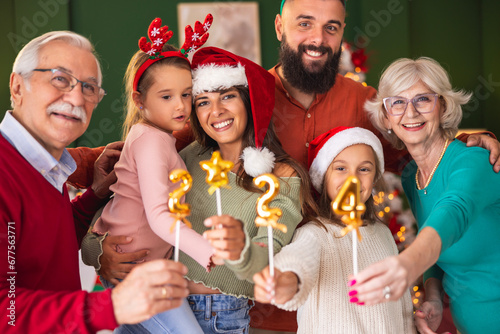 Family celebrating New Year holding little balloons shaped as numbers 2024