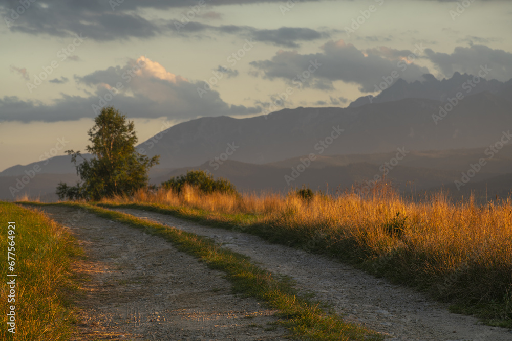 Gravel road with mountains in the background during sunset