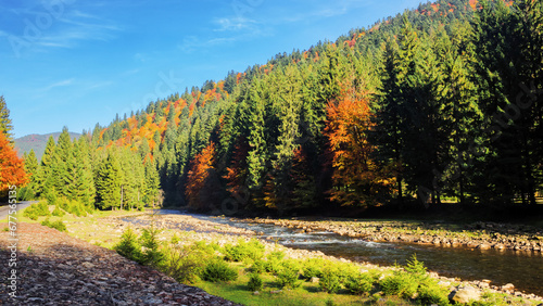 river flows through countryside valley. mountainous forested landscape on a sunny day in autumn