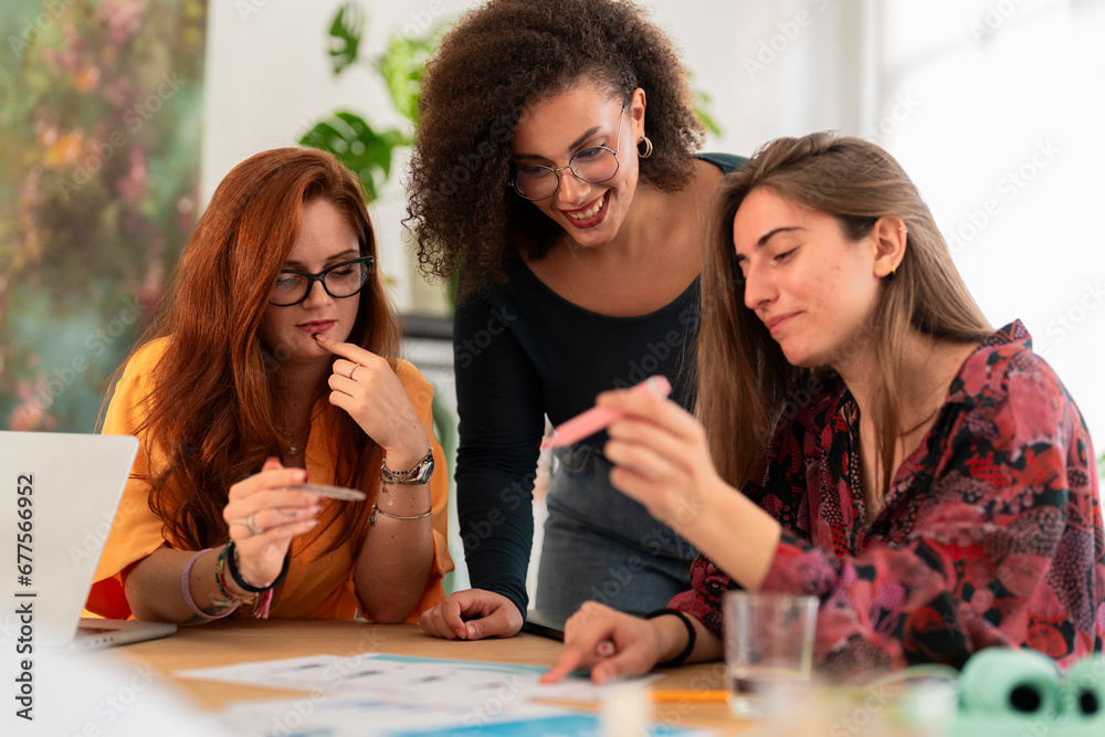 Positive young female coworkers in casual clothes gathered at wooden ...