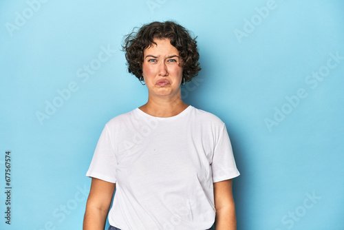 Fotografija Young Caucasian woman with short hair blows cheeks, has tired expression