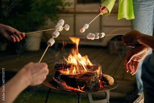 Closeup roasted marshmallows on skewers over open camping bonfire