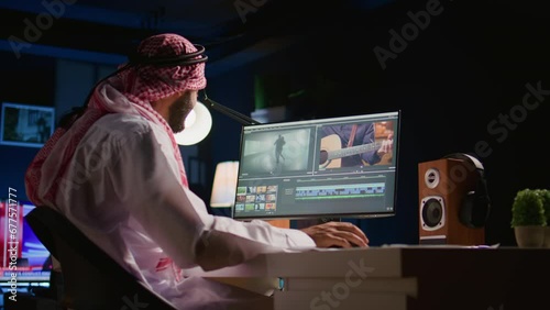 Arabic colorist freelancer wearing headphones while editing project, stitching videos together, working with images and sounds. Self employed man processing movie on PC workstation photo