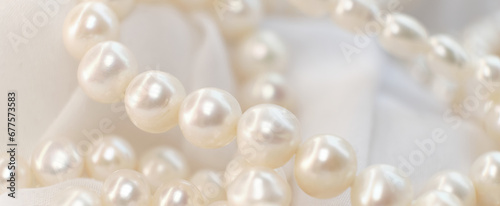 A cascade of pearls rests on a soft, white cloth, their natural luster dimly reflecting light. The delicate arrangement echoes the timeless appeal of authenticity in a world chasing after the