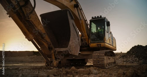 Construction Site On Sunny Evening: Industrial Excavator Driving To Complete Work Tasks Related To Building New Real Estate Project. Man Operating Heavy Machinery To Build New Apartment Complex. photo