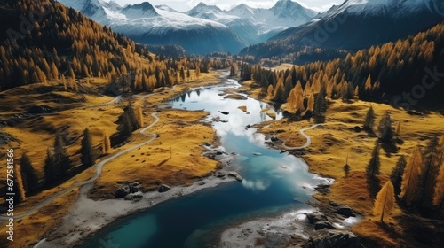 Aerial view of snowy mountains and a small lake in the middle, Autumn forest surrounding.