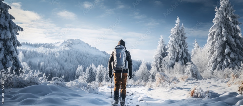The active man chose to travel during winter to embrace the beauty of nature enjoying the snow covered forest and reaping the health benefits of being in the outdoors which made him happy du - obrazy, fototapety, plakaty 