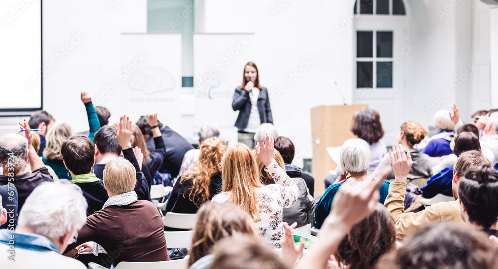 Obraz premium I have a question. Group of people sitting at the chairs in conference hall, raising their hands. Workshop at university. Business and Entrepreneurship event.