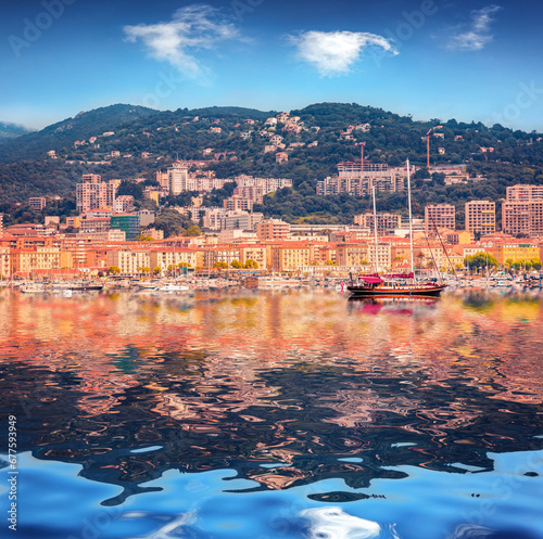 Yachts, boats and colorful buildings of Ajaccio port reflection in the calm waters of Mediterranean sea. Amazing morning scene of Corsica island, France, Europe. Traveling concept background.
