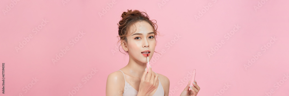 A smiling woman holding lip gloss and looking at tube, getting ready for work or party, A smiling woman holding lip gloss and looking at tube, getting ready for work or party,