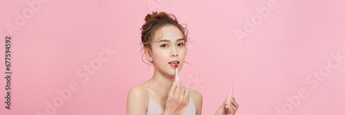 A smiling woman holding lip gloss and looking at tube, getting ready for work or party,