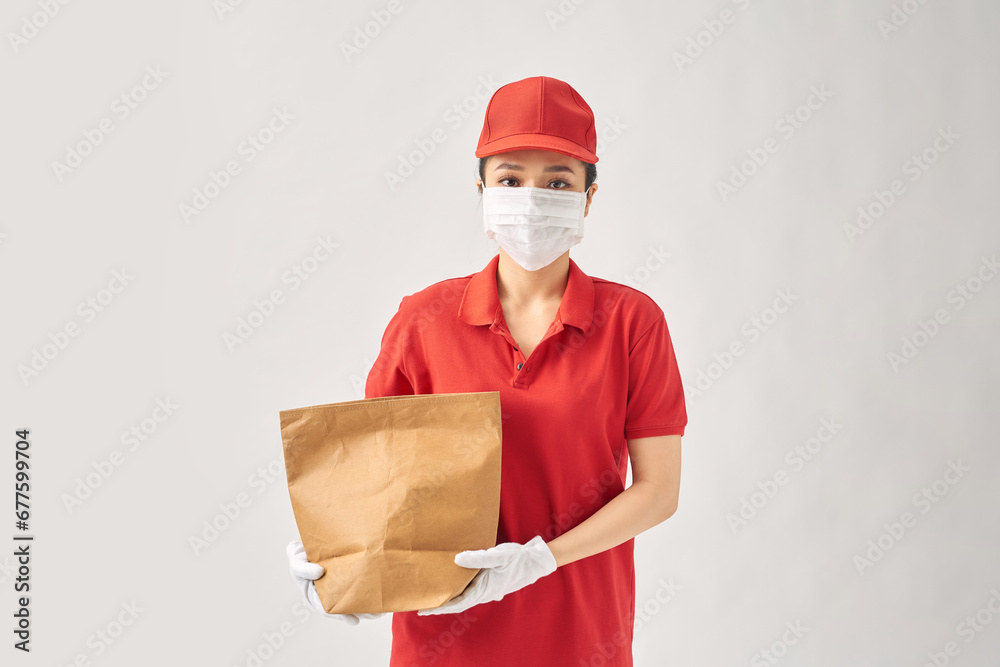 Young smiling asian delivery woman in red uniform holding paper bag food delivery Young smiling asian delivery woman in red uniform holding paper bag food delivery