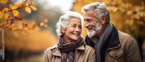 Portrait of happy senior couple walking in autumn park. They are looking at each other and smiling
