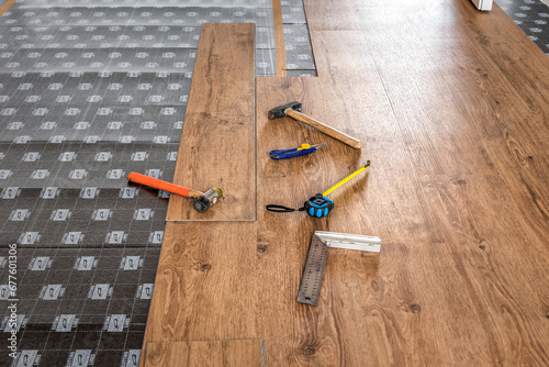 Hammer, ruler with angle bar, tape meter and other tool on laminate vinyl floor