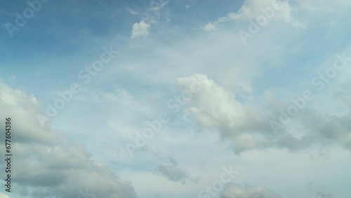 Time lapse of many clouds floating in the breeze in a clear daytime sky.